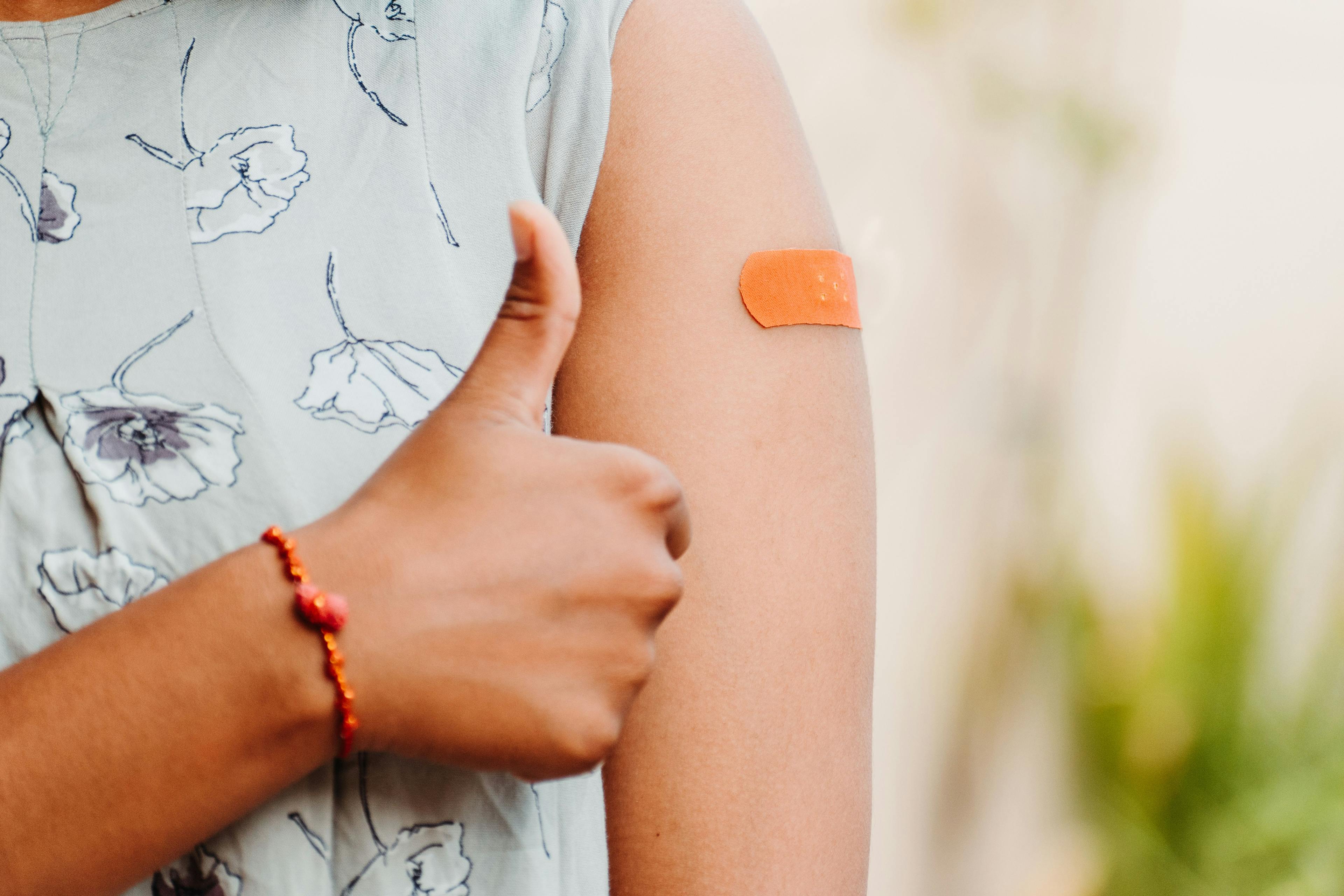 Teen giving thumbs up after getting vaccinated and showing bandage on her arm:    (Adobe Stock by Yashvi)