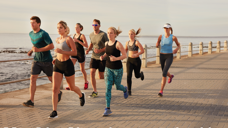 a group of people jogging on the boardwalk by the ocean