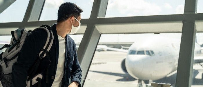 Young man looking out at a plane at the airport. 