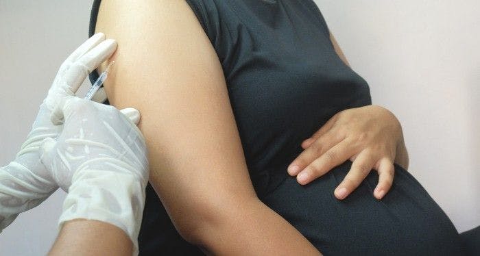 brown-skinned pregnant woman getting covid-19 vaccine