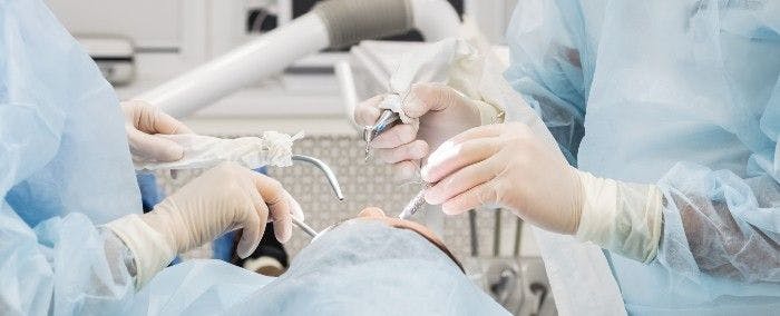 Close-up of the hands of a dentist and nurse surgeon over an operating room during a dental implant operation.  (Adobe Stock 314873958 by Валентина Баранова.)