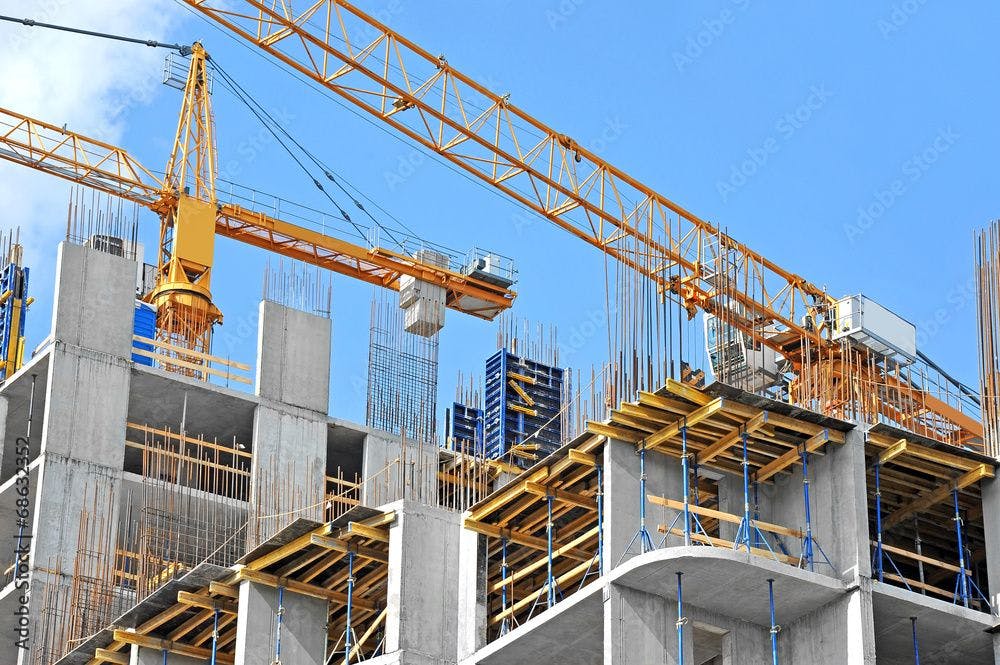 Crane and building construction site against blue sky ©Unkas Photo stock.adobe.com
