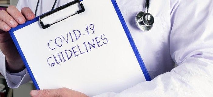 Covid-19 guidelines written on a folder held by a health care worker